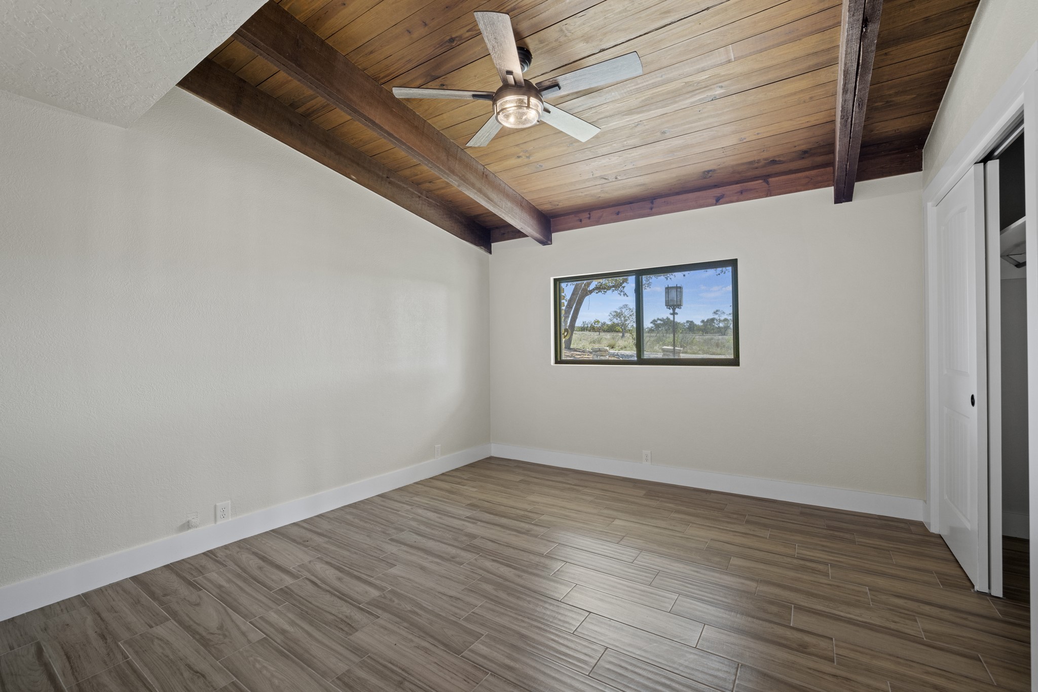 241 Highway 87 Comfort, TX 78013 - Photo 15 of 40 an empty room with wooden floor ceiling fan and windows