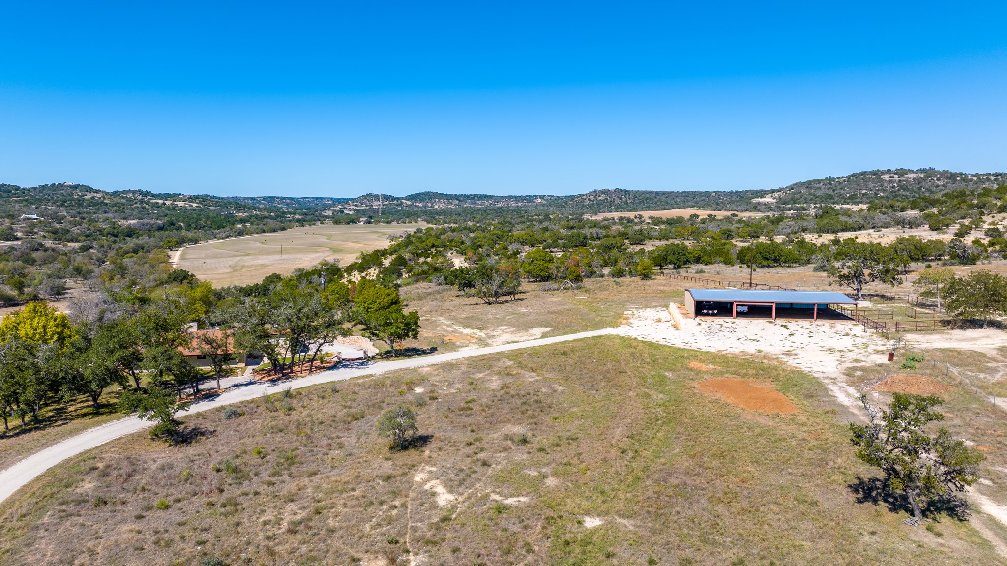 241 Highway 87 Comfort, TX 78013 - Photo 34 of 39 Expansive undeveloped property featuring a long driveway, a single-story building with a metal roof, and scattered mature trees across the landscape
