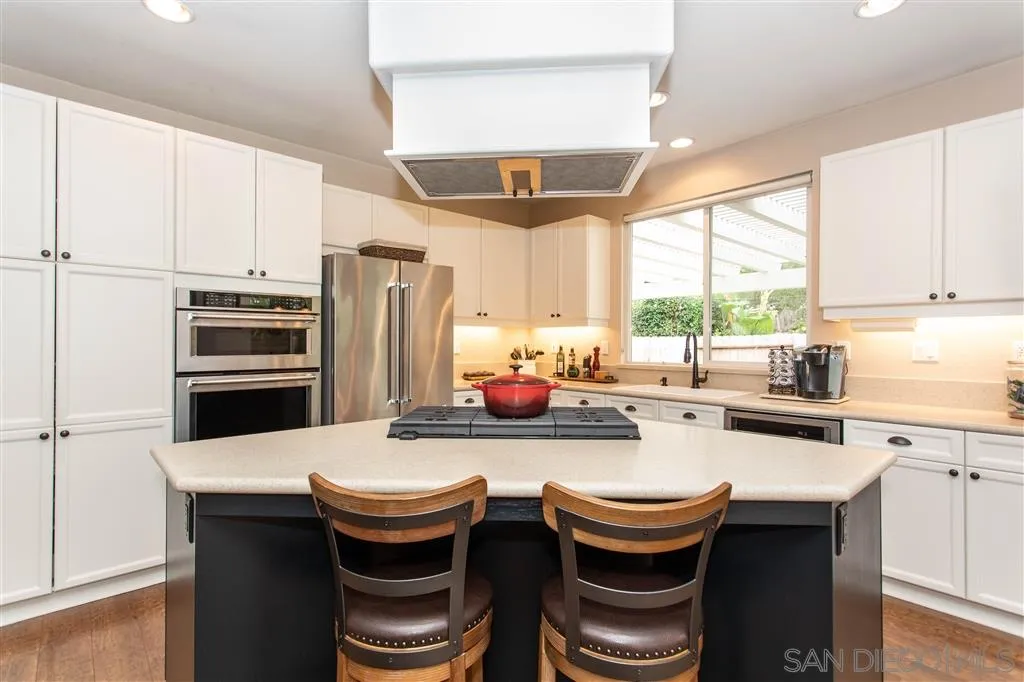 a kitchen with stainless steel appliances a stove a refrigerator and white cabinets