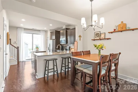 a view of a dining room and livingroom with furniture wooden floor a chandelier