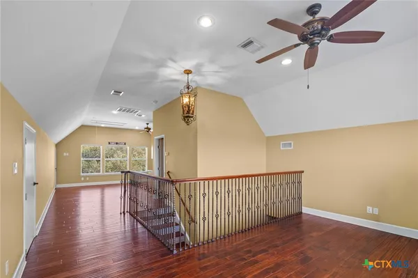 a view of a hallway with wooden floor and a ceiling fan