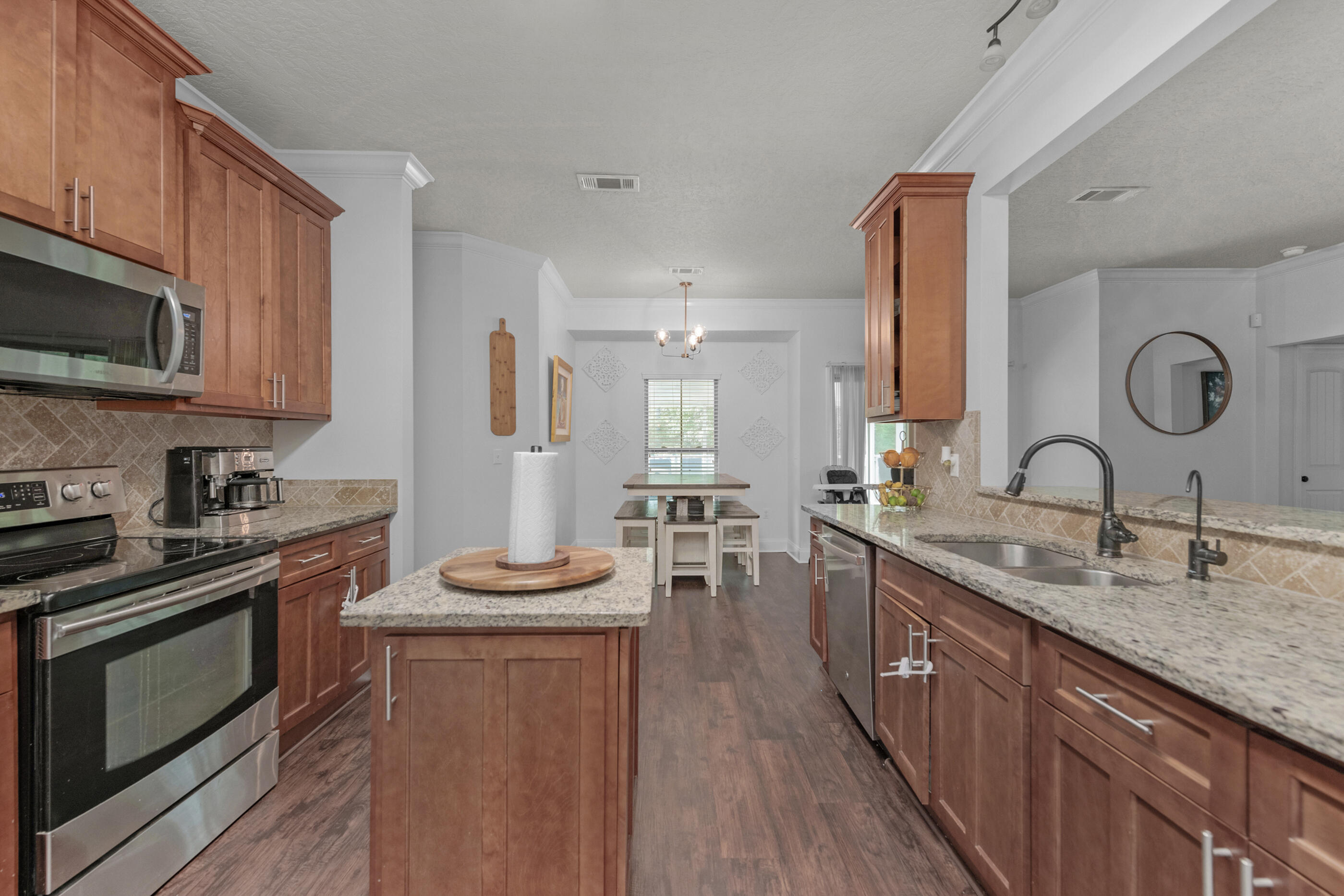 4509 Beth Circle Crestview, FL 32539 - Photo 5 of 29 a kitchen with stainless steel appliances granite countertop a stove a sink dishwasher a microwave oven and a dining table with wooden floor
