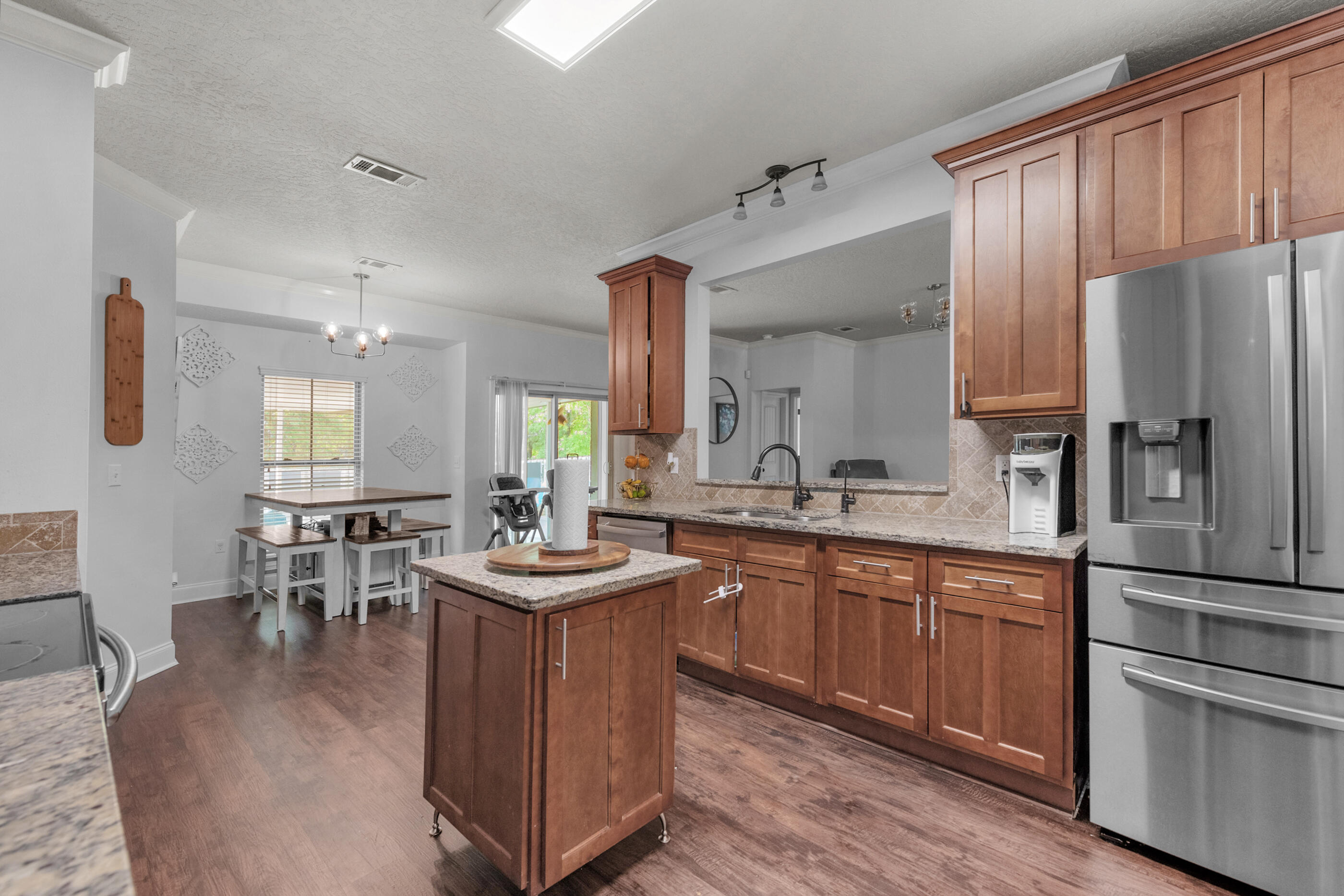 4509 Beth Circle Crestview, FL 32539 - Photo 6 of 29 a kitchen with stainless steel appliances granite countertop a refrigerator a sink dishwasher a stove and a dining table with wooden floor