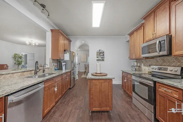 a kitchen with stainless steel appliances granite countertop wooden cabinets stove top oven and sink