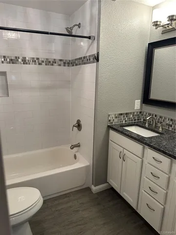 a bathroom with a granite countertop sink mirror vanity and toilet