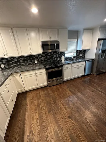 a kitchen with granite countertop white cabinets and stainless steel appliances