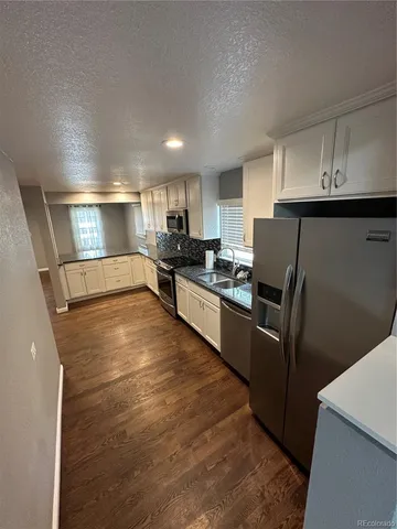 a kitchen with granite countertop a refrigerator and a sink