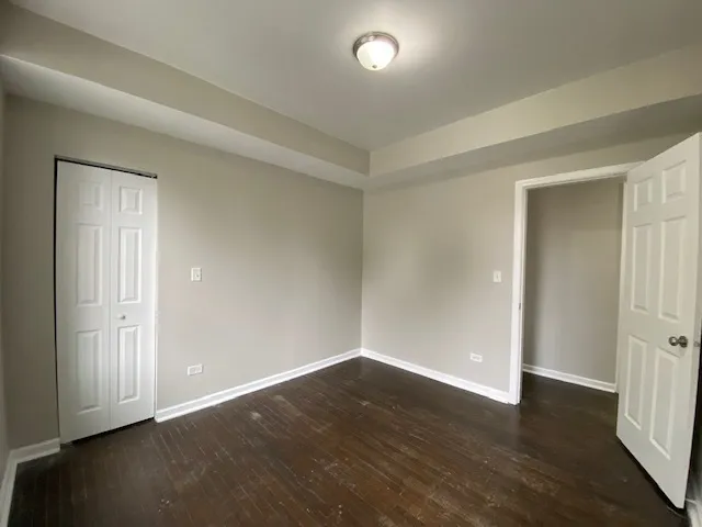 a view of an empty room with wooden floor and closet area