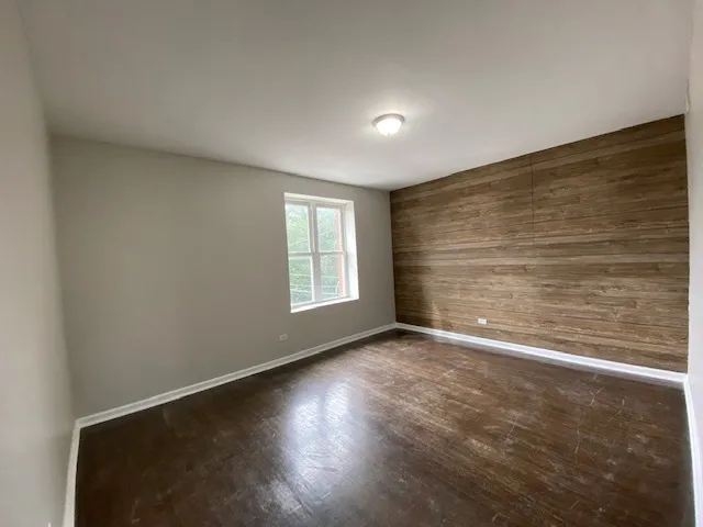 an empty room with wooden floor and windows with curtains