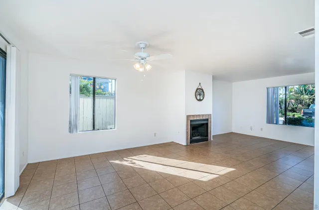 an empty room with windows and fireplace