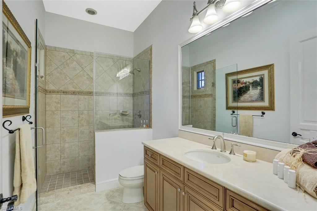 16649 Toscana Circle, Unit 806 Naples, FL 34110 - Photo 25 of 35 a bathroom with a granite countertop sink a toilet a shower and a mirror