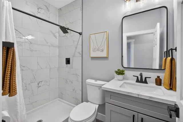 a bathroom with a granite countertop sink toilet and shower