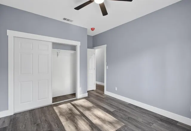 an empty room with ceiling fan and window