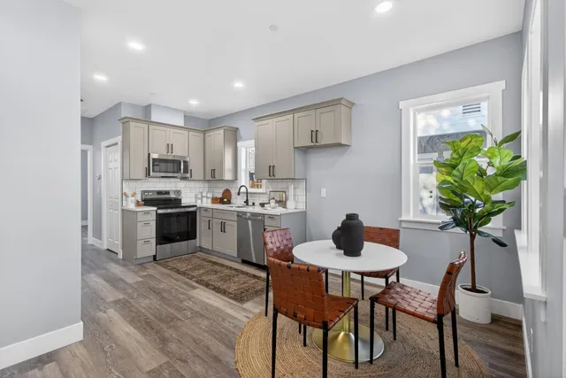 a kitchen with granite countertop white cabinets stainless steel appliances and a dining table
