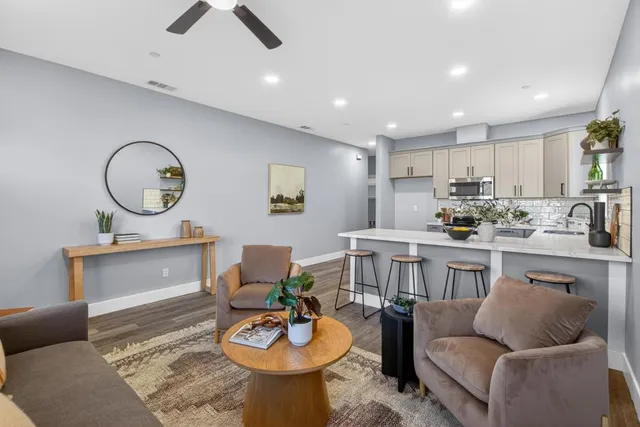 a living room with furniture a rug and kitchen view