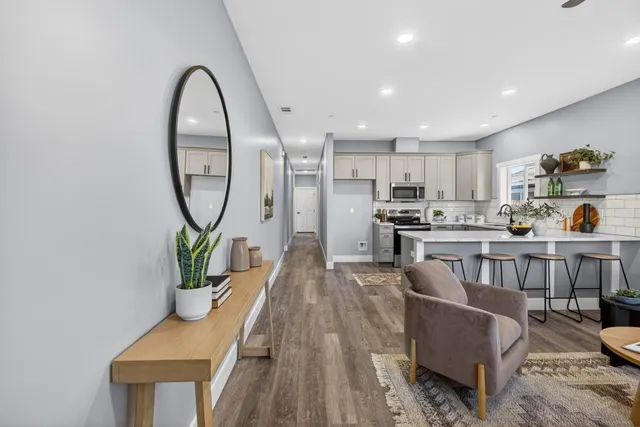 a living room with furniture a mirror and a potted plant