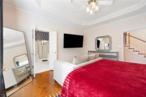 a bedroom with a bed a flat screen tv and a chandelier