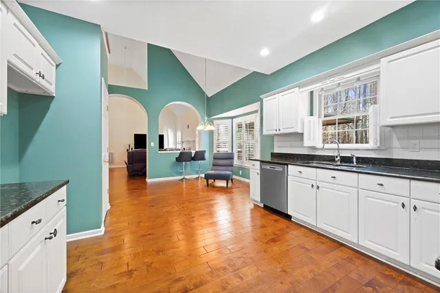 a large kitchen with stainless steel appliances granite countertop a large window and a wooden floors