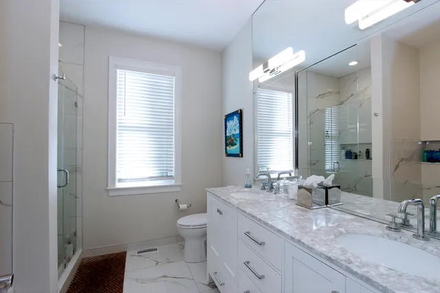 a bathroom with double vanity sink a toilet and a mirror