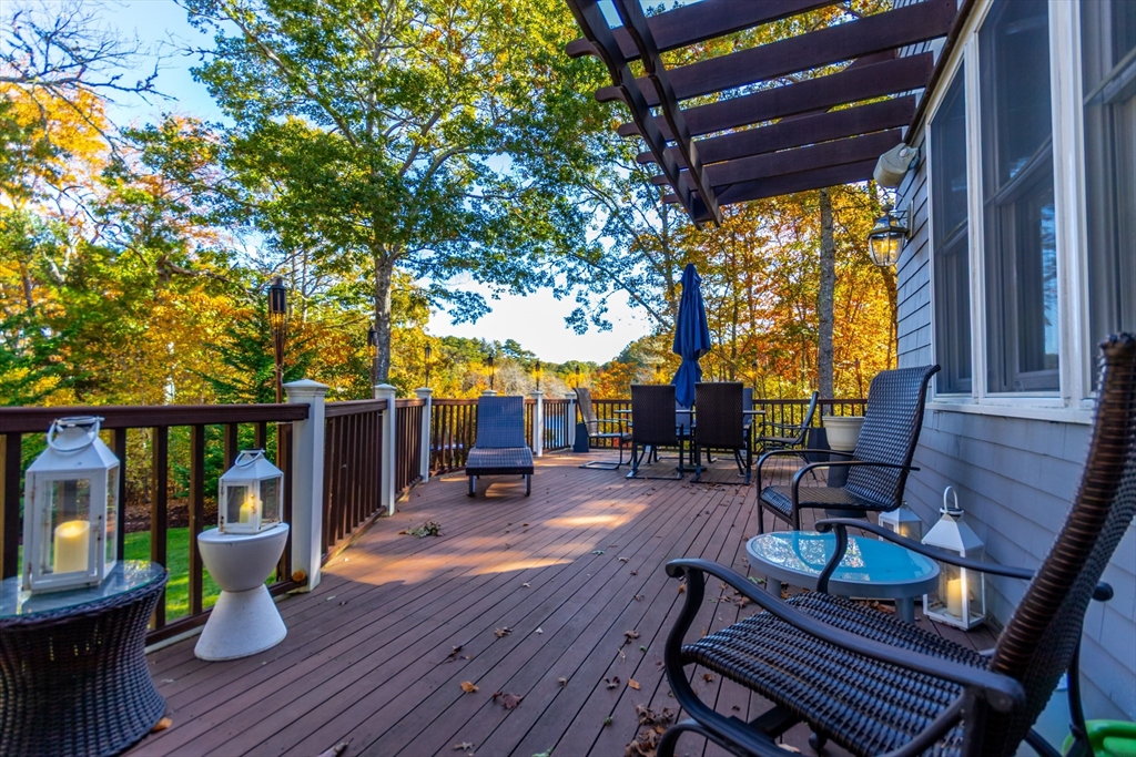 42 Fells Pond Road Mashpee, MA 02649 - Photo 32 of 35 a view of a patio with table and chairs potted plants and wooden floor