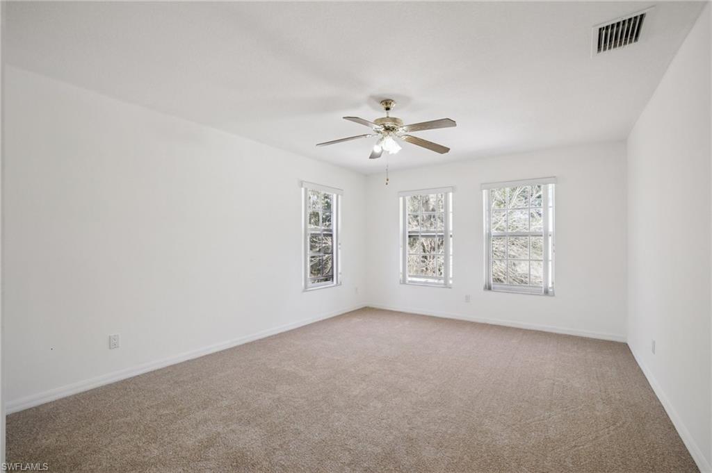 5348 Cypress Lane Naples, FL 34113 - Photo 24 of 28 an empty room with windows and ceiling fan