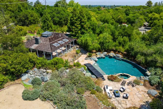 an aerial view of residential house with outdoor space and trees all around