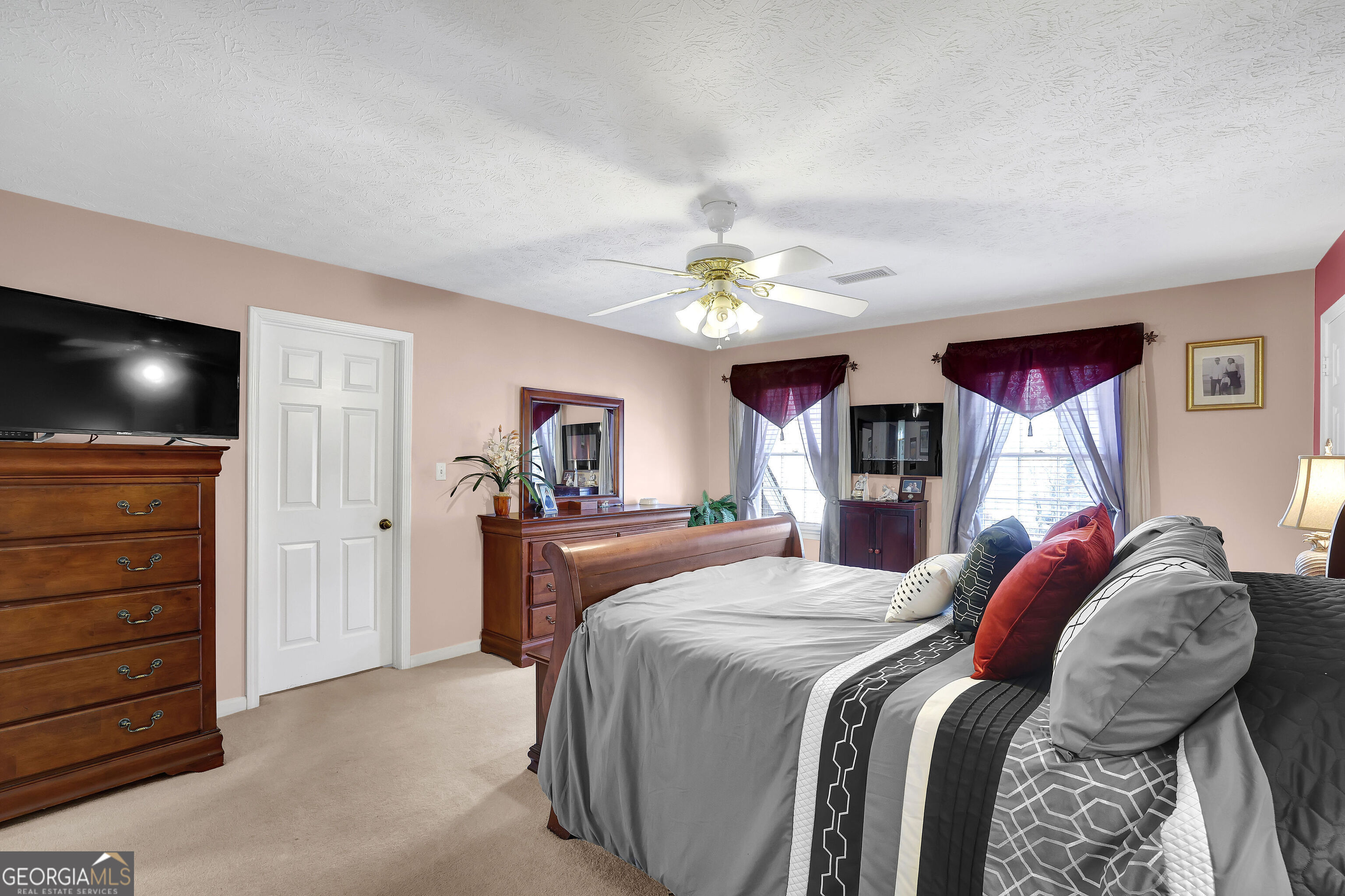 2613 Travois Way Southwest Lilburn, GA 30047 - Photo 19 of 40 a bedroom with a large bed and a flat screen tv