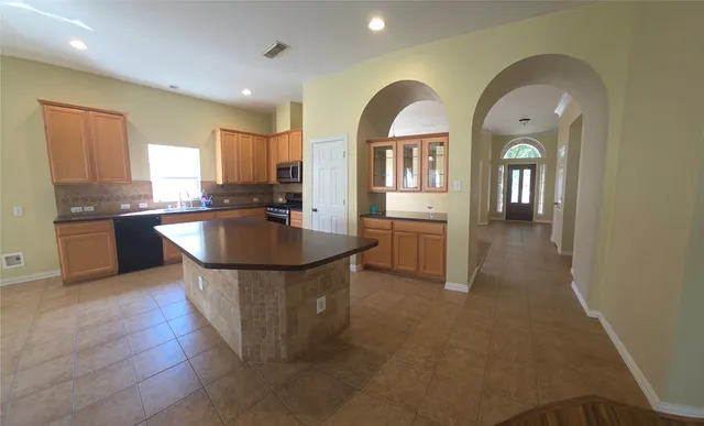a kitchen with stainless steel appliances granite countertop a sink a counter space and living room