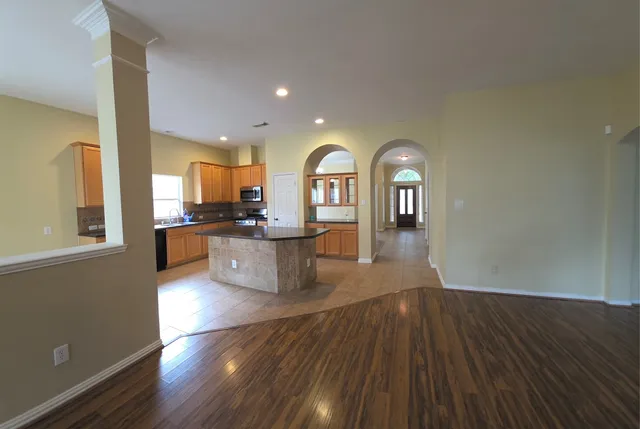 a view of a living room a wooden floor and a kitchen view