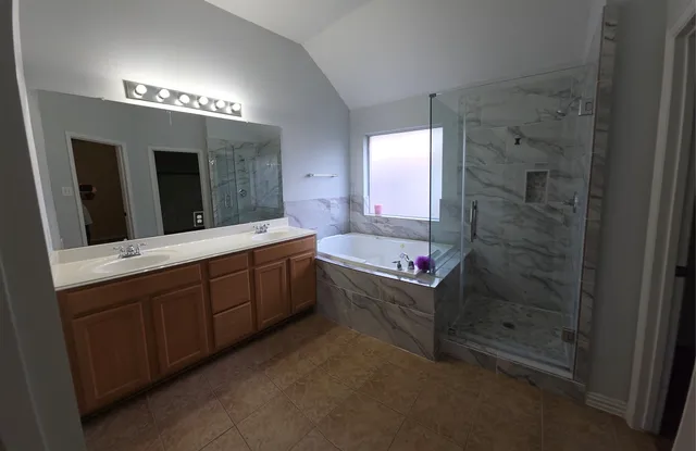 a spacious bathroom with a double vanity sink a large mirror and a shower