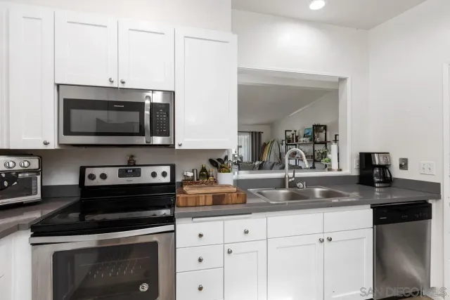 a kitchen with granite countertop white cabinets and black appliances