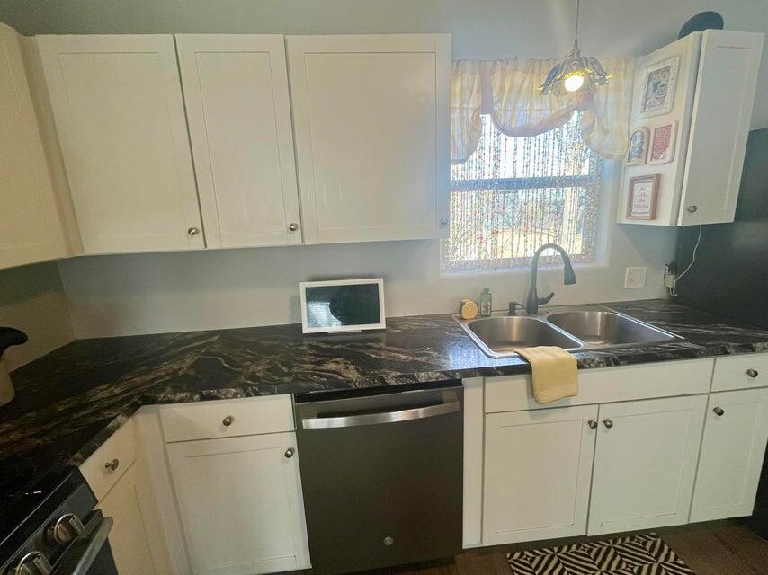 1209 Xenia Street Plainview, TX 79072 - Photo 11 of 31 a kitchen with granite countertop a sink a stove a microwave and cabinets