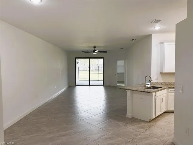 an empty room with a chandelier fan and windows