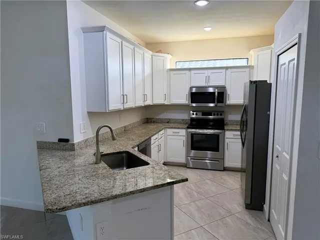 a kitchen with stainless steel appliances granite countertop a stove a refrigerator and a sink