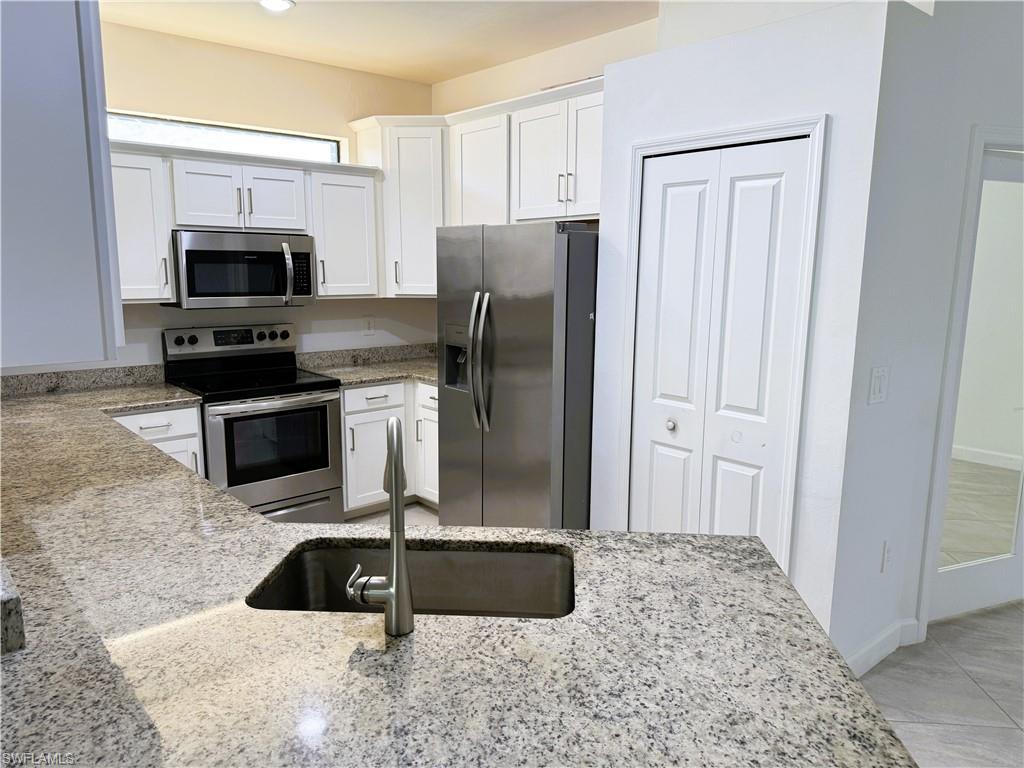 14063 Winding Cedar Way Fort Myers, FL 33913 - Photo 7 of 15 a kitchen with stainless steel appliances granite countertop a stove a refrigerator and a sink