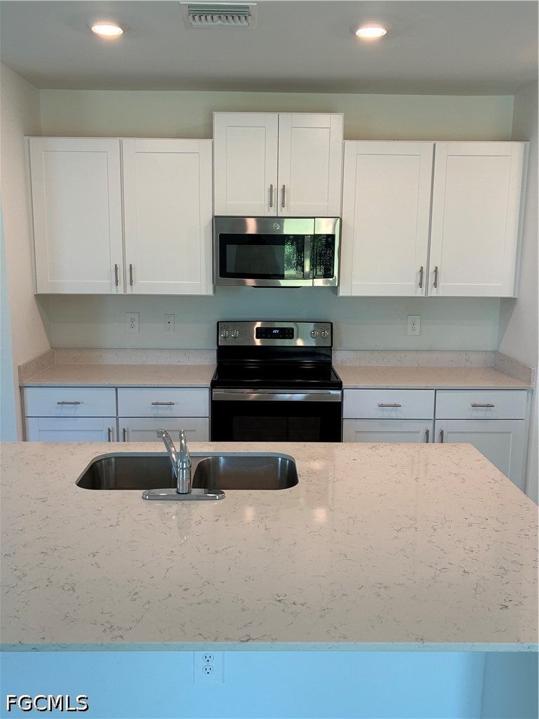 12441 Dakota Ridge Place Lehigh Acres, FL 33974 - Photo 8 of 16 a kitchen with granite countertop a sink a stove and cabinets