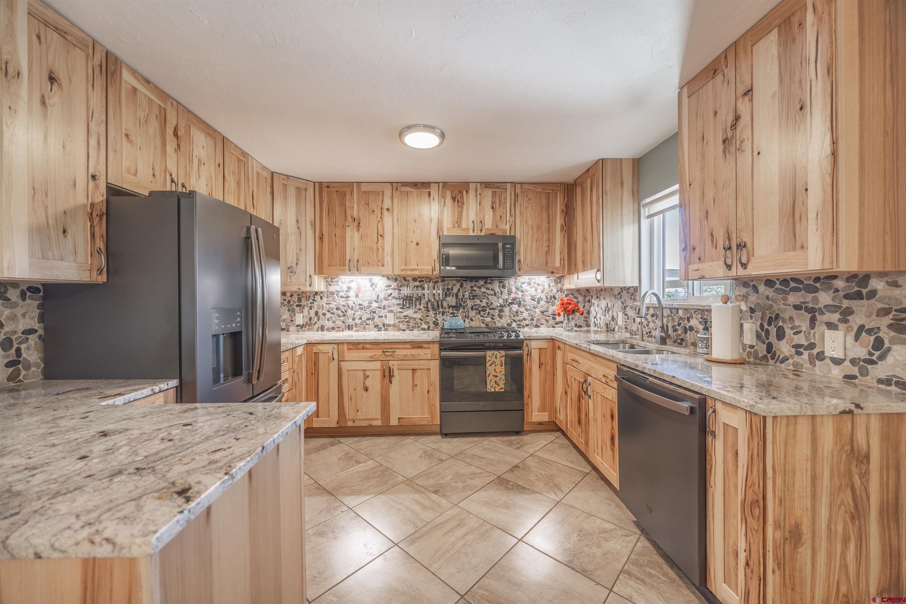 16574 6275th Road Montrose, CO 81403 - Photo 9 of 45 a kitchen with stainless steel appliances granite countertop a stove a sink dishwasher a refrigerator and cabinets with wooden floor