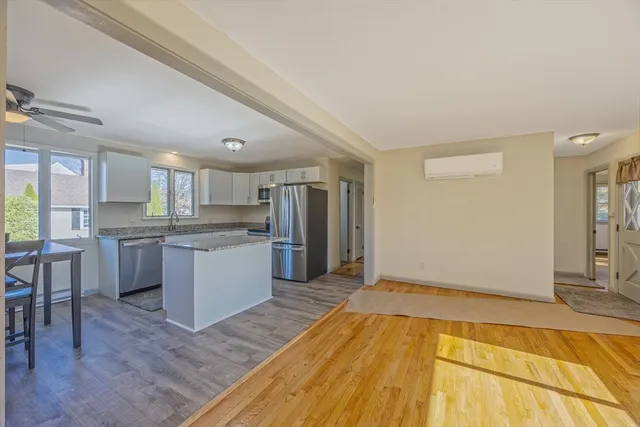 a kitchen with stainless steel appliances granite countertop a refrigerator a stove a sink a dining table and chairs with wooden floor