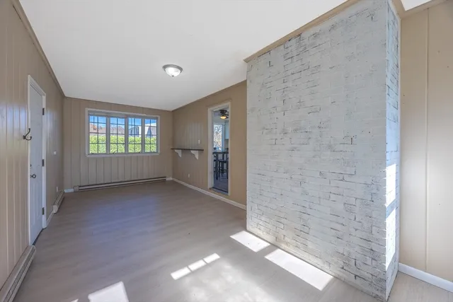 a view of an empty room with wooden floor and windows