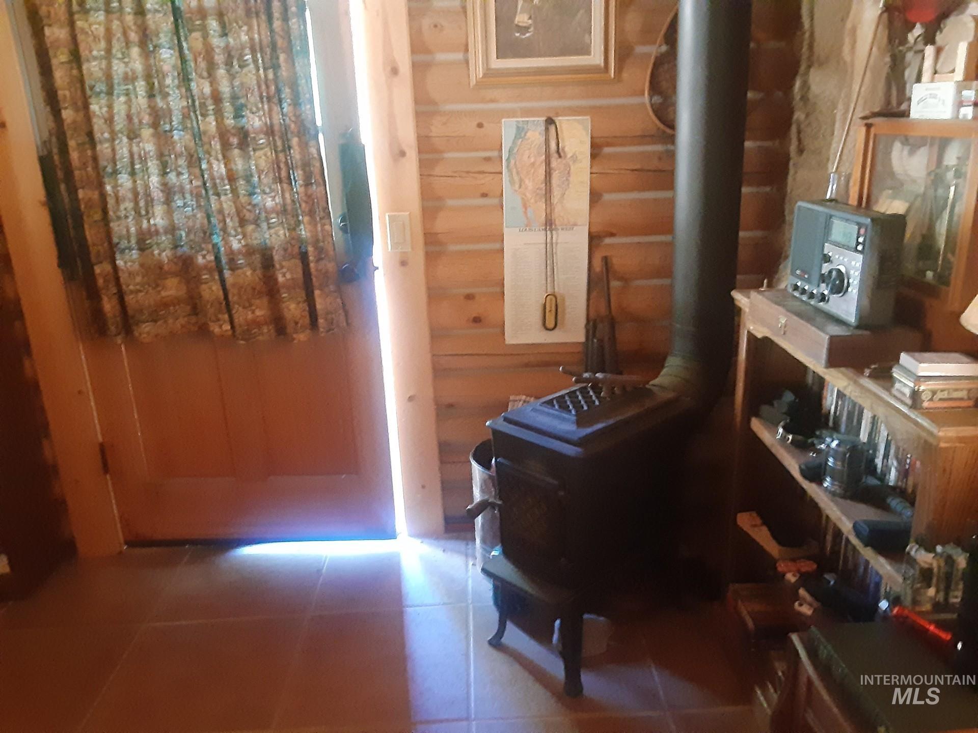 2074 Fleck Smt Road Fairfield, ID 83327 - Photo 11 of 22 Sitting room with a wood stove, log walls, and tile patterned flooring
