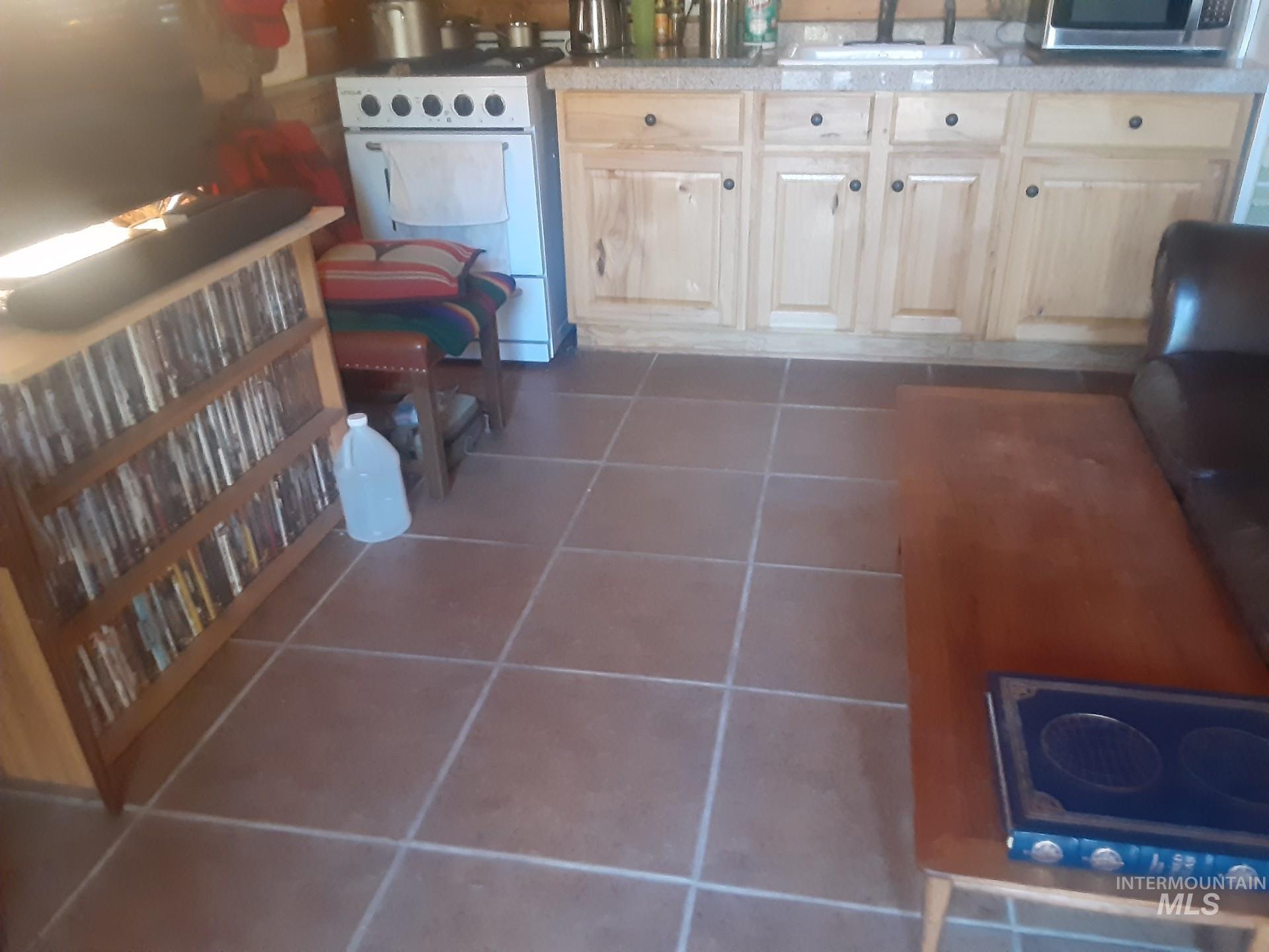 2074 Fleck Smt Road Fairfield, ID 83327 - Photo 6 of 22 Kitchen with dark tile patterned floors, white stove, stainless steel microwave, electric cooktop, and light countertops