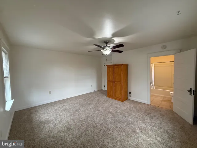 an empty room with a chandelier fan and windows