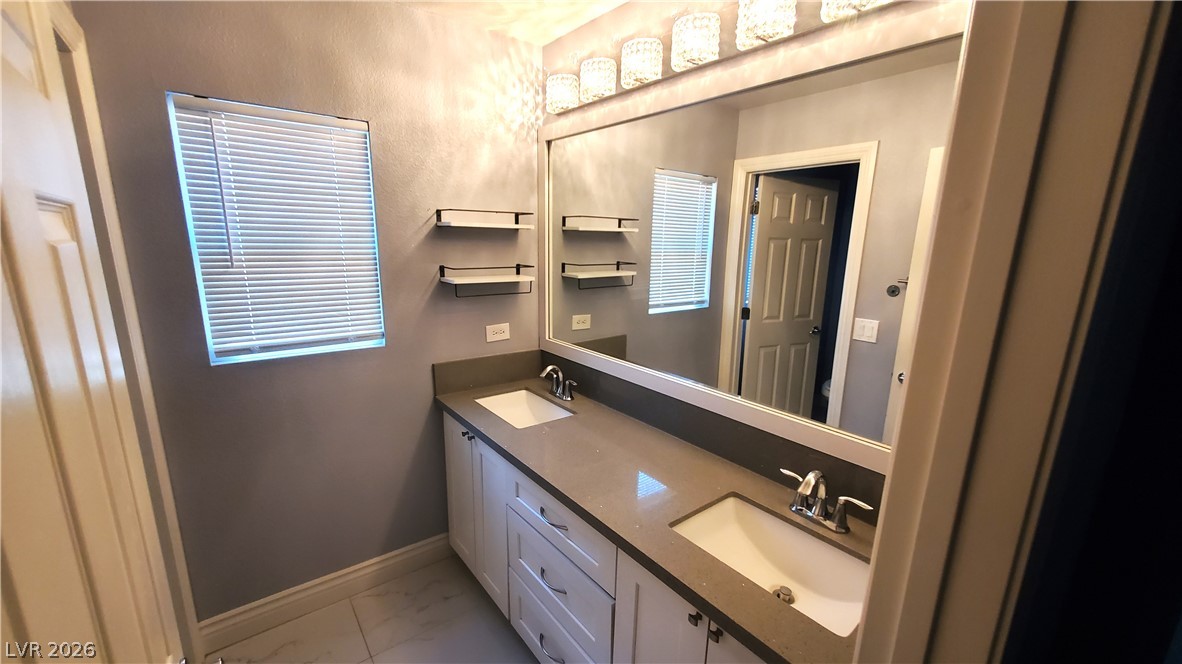 7903 Dell Ridge Avenue Las Vegas, NV 89179 - Photo 14 of 20 Double vanity with sleek countertops offers convenience and functionality in this well-appointed bathroom.