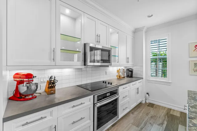 a kitchen with stainless steel appliances granite countertop a stove top oven a refrigerator a dining table and chairs with wooden floor