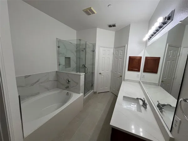 a bathroom with a tub a sink and glass door