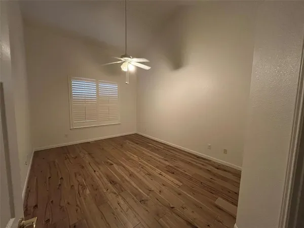 an empty room with wooden floor chandelier and window