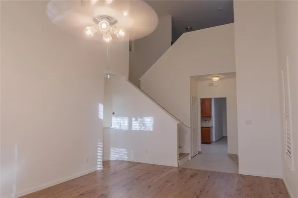 a view of an empty room with wooden floor and a ceiling fan