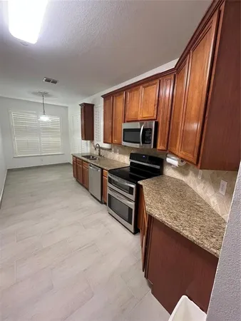 a kitchen with stainless steel appliances granite countertop a stove a sink and a refrigerator