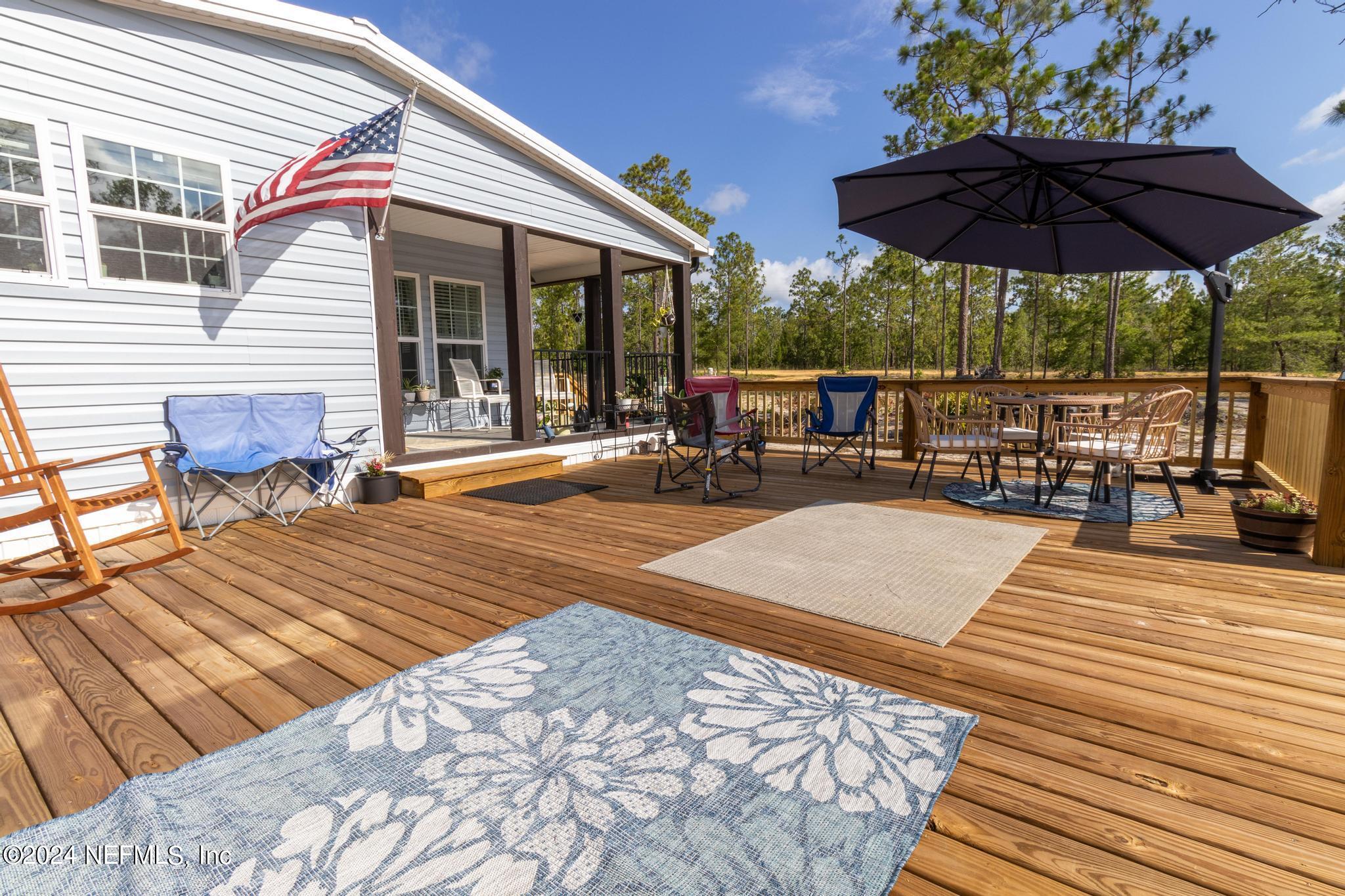 121 Honeysuckle Trail Hawthorne, FL 32640 - Photo 11 of 44 a view of a roof deck with table and chairs under an umbrella with wooden floor
