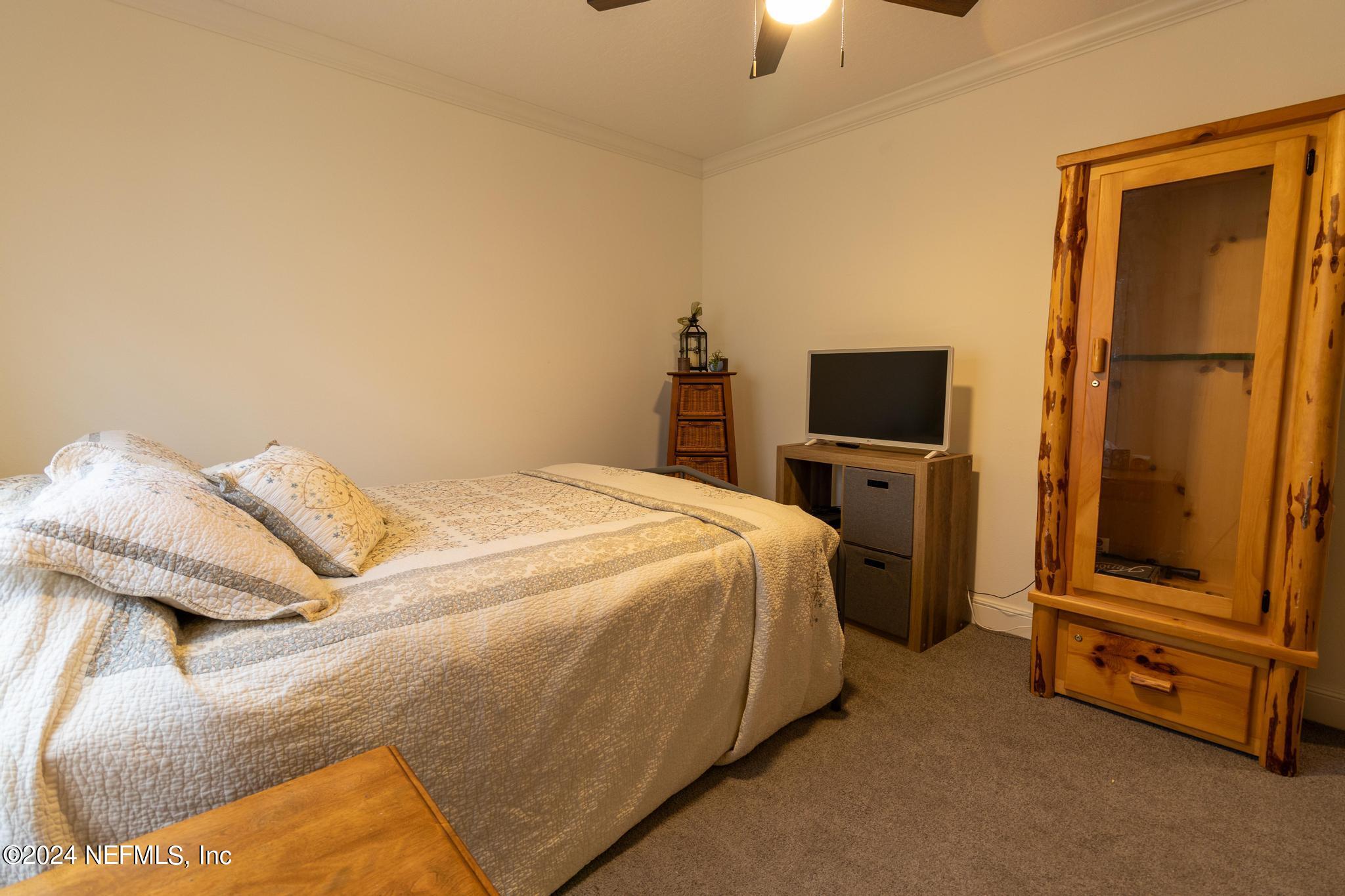 121 Honeysuckle Trail Hawthorne, FL 32640 - Photo 18 of 44 a bedroom with a bed flat screen tv and chandelier